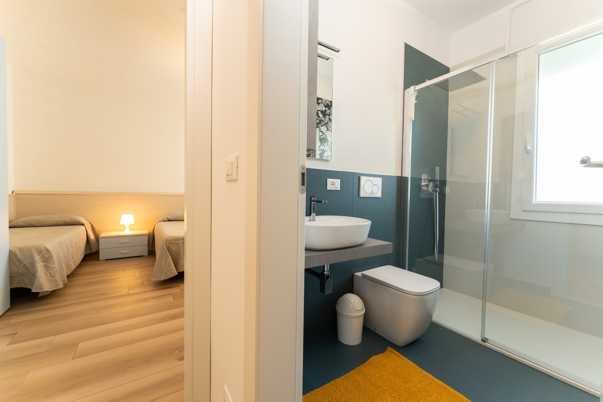 Metà della camera da letto con due letti e vista sul bagno.