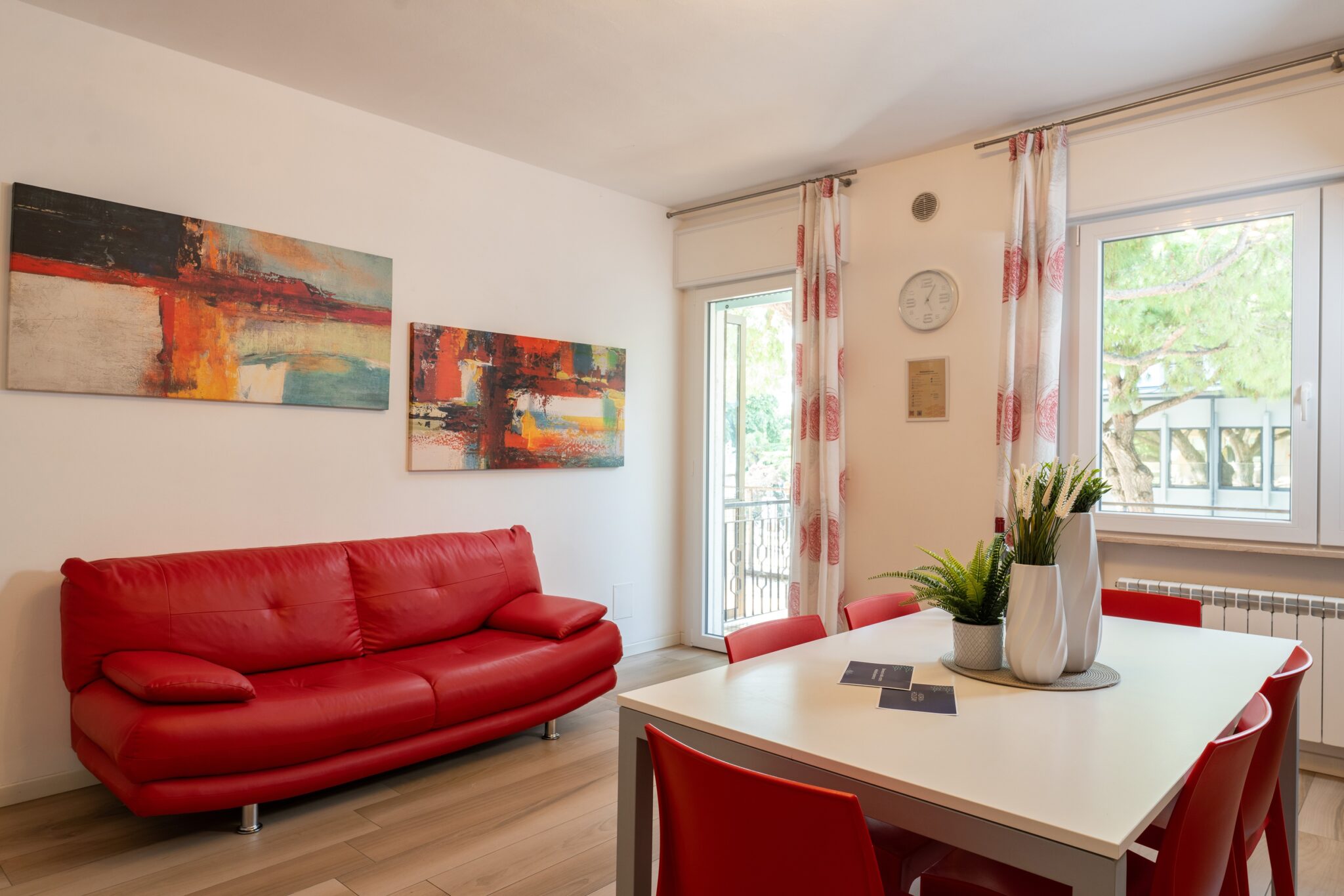 Un divano rosso con tavolo bianco e sedie rosse in cucina.